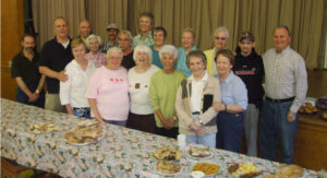 group of people in front of a table of food at the soup kitchen