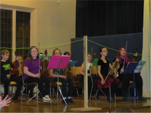 A group shot of young students all playing violins