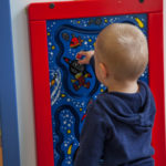 Toddler playing with a board with space pictures on it